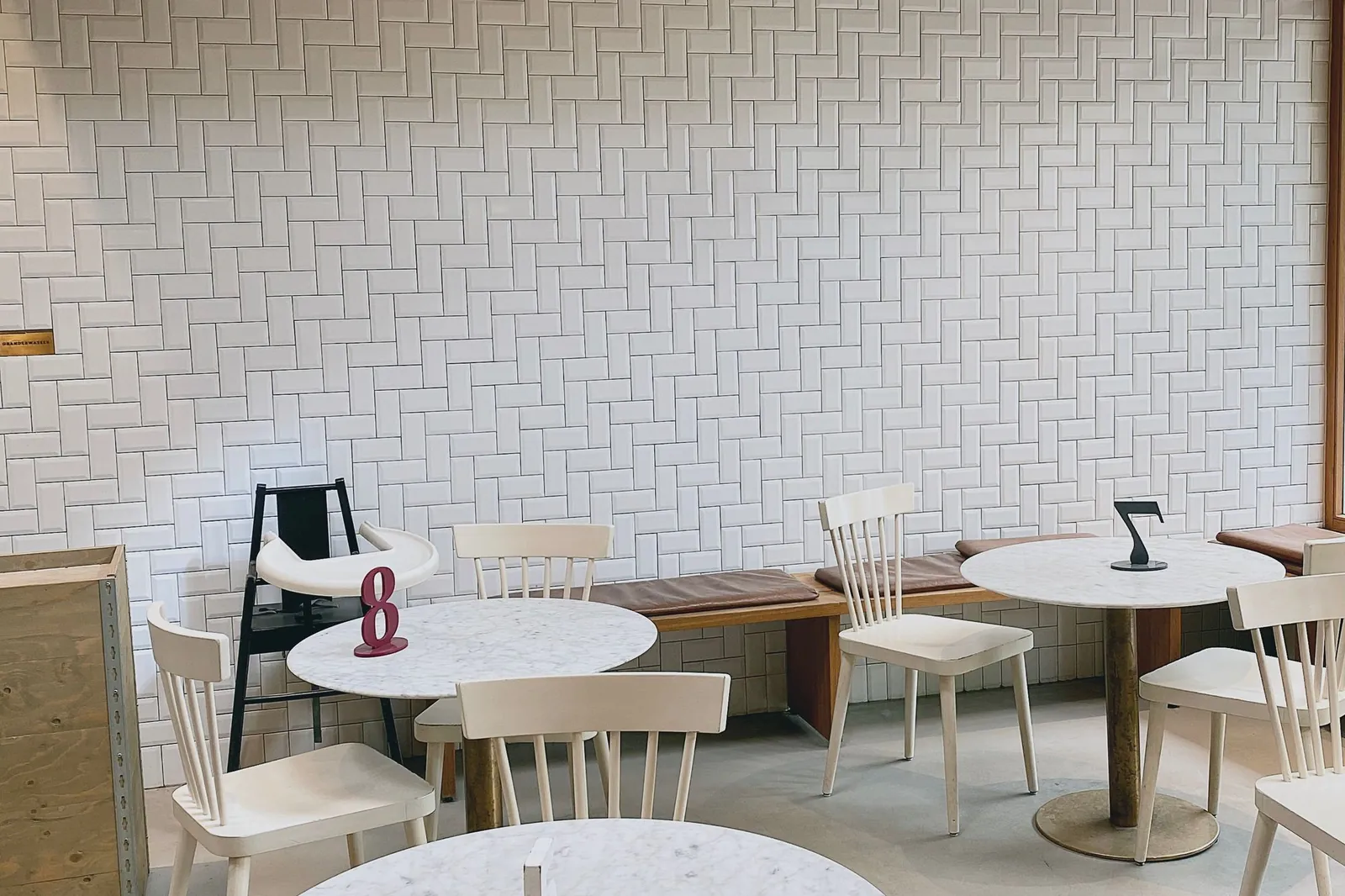 Beyaz yuvarlak masalar ve sandalyelerle döşenmiş modern bir kafenin iç mekânı