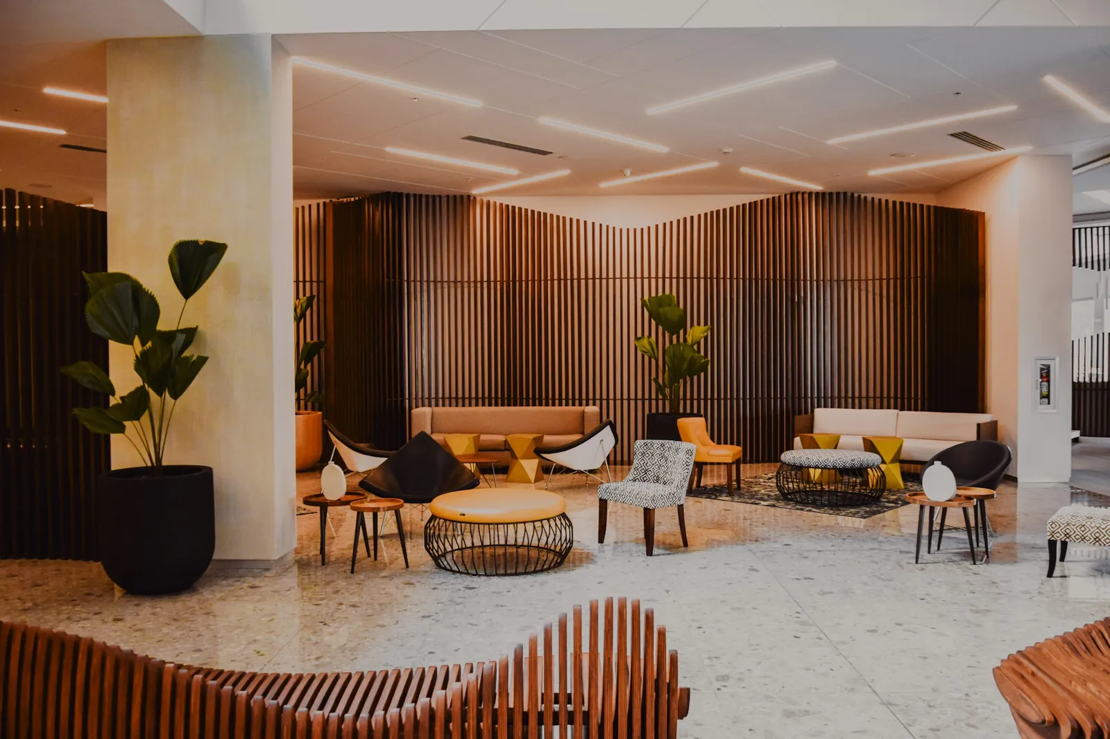 Ahşap kaplama duvarlar ve tasarım koltuklarla döşenmiş modern bir otel lobisi